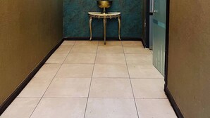 A hallway with a decorative wall, a clock, and a small table with a plant.