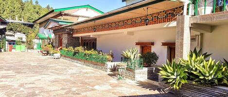 A courtyard with stone flooring, a covered seating area, and potted plants.