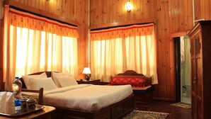 Habitación de hotel con paneles de madera, una cama con ropa blanca, una mesita de noche con lámpara y un armario de madera.