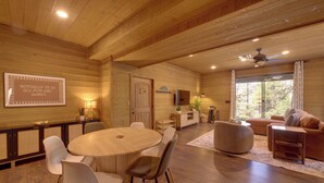 A spacious room with a wooden ceiling, a round dining table with chairs, a sofa, and a television. - Sunset Views + Scenic Trails: Spacious Pine Escape (Pine)