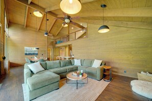 A spacious living area with a large sectional sofa, a round coffee table, and a ceiling fan. - Sunset Views + Scenic Trails: Spacious Pine Escape (Pine)