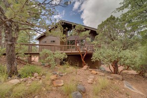 A cabin with a wooden deck, surrounded by trees and rocks. - Sunset Views + Scenic Trails: Spacious Pine Escape (Pine)