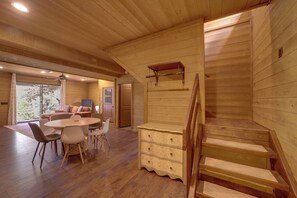 Un intérieur en bois comprenant un coin repas, un escalier et une vue par une fenêtre.