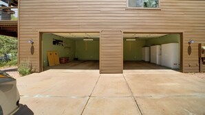 A two-car garage with a concrete floor, a green wall, and a window with curtains. - Sunset Views + Scenic Trails: Spacious Pine Escape (Pine)