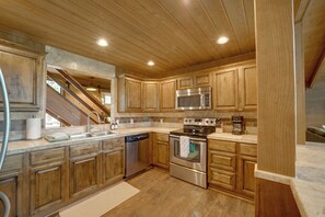 Une cuisine moderne avec des meubles en bois, des appareils électroménagers en acier inoxydable et un four encastré.