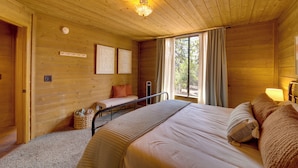 A wooden cabin room with a bed, a bench, and a window with curtains. - Sunset Views + Scenic Trails: Spacious Pine Escape (Pine)