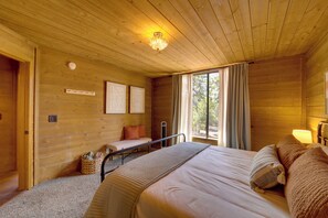 Ein Zimmer in einer Holzhütte mit einem Bett, einer Bank und einem Fenster mit Vorhängen.