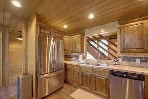 Eine moderne Küche mit Edelstahlgeräten, Holzschränken und einer Küchenrückwand aus Stein.