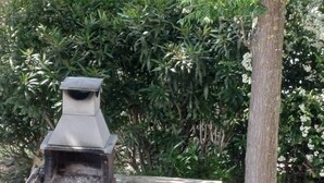 A barbecue grill with a chimney, a table, and a blue bag on the ground. - Quiet 3-Bedroom Apartment Povoa (Póvoa de Santa Iria)