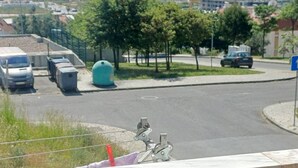 A parking area with a bicycle, a blue sign, and a view of a bridge and water body. - Quiet 3-Bedroom Apartment Povoa (Póvoa de Santa Iria)