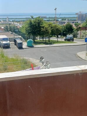 A parking area with a bicycle, a blue sign, and a view of a bridge and water body. - Quiet 3-Bedroom Apartment Povoa (Póvoa de Santa Iria)