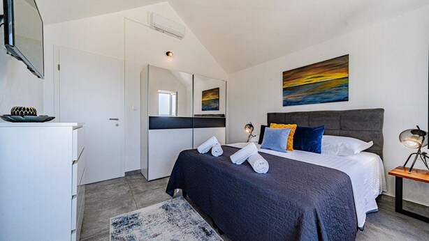 Ein modernes Schlafzimmer mit Bett, Nachttisch und einem Bild an der Wand.