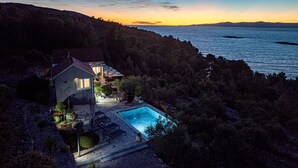 Ein Haus mit Schwimmbad, umgeben von Bäumen und mit Blick auf ein Gewässer.