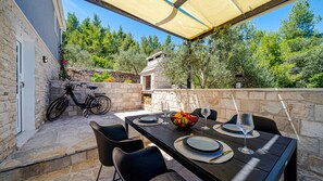 An outdoor dining area with stone walls, a table set for two, and a bicycle parked nearby. - Holiday home Dubravka by Villas Guide (Blato)