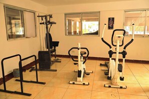 A gym with exercise equipment, including a treadmill, elliptical, and weight machines. - Kilimani Penthouse with Skyline Views Pool & Wi-Fi (Nairobi)