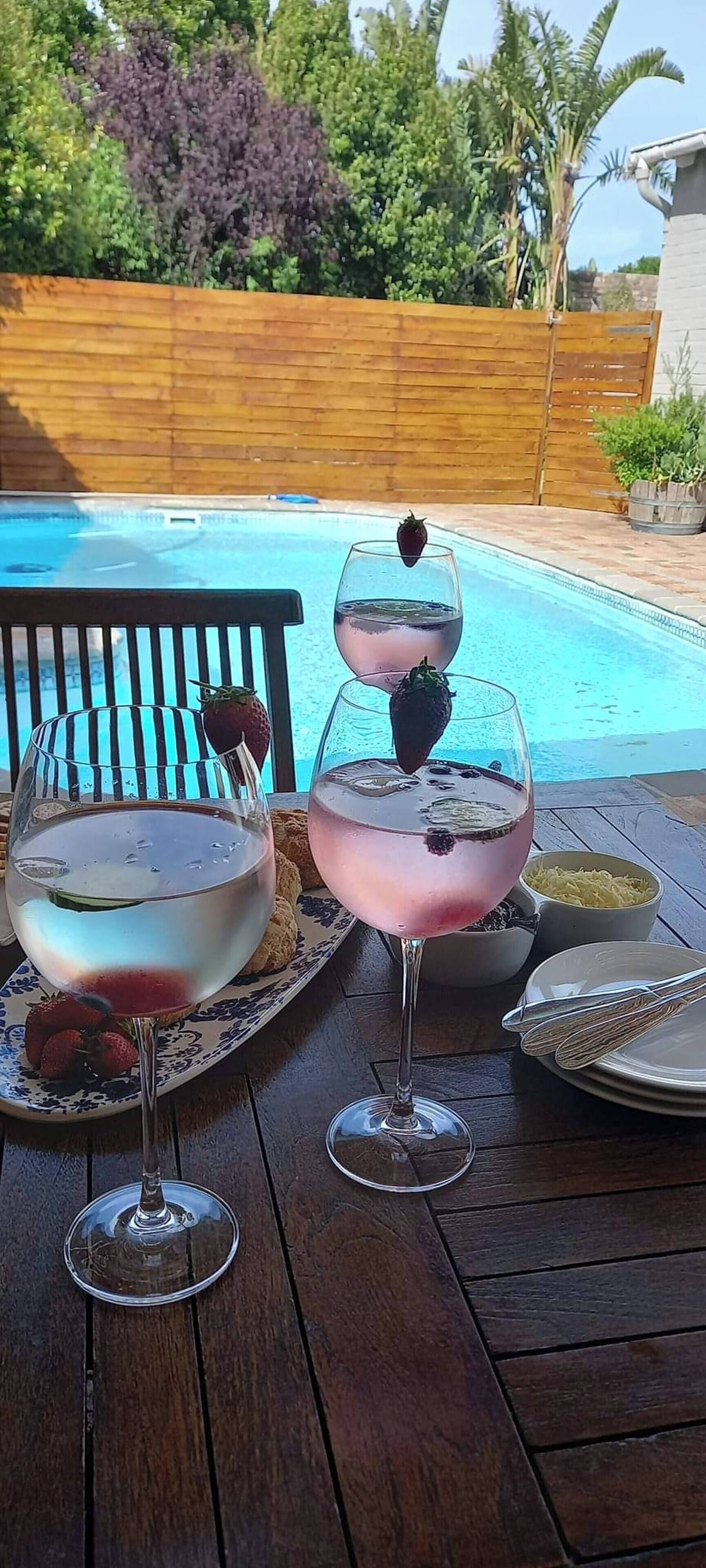 Deux cocktails aux fraises, servis sur une terrasse en bois au bord d’une piscine.