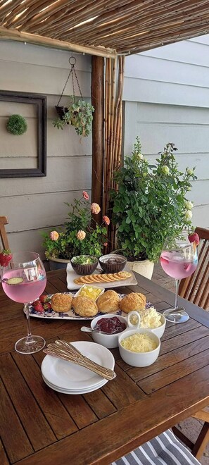 An outdoor dining area with a table set for a meal, including bread, butter, and a drink. - Cornerhouse Family Retreat (Cape Town)