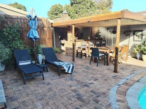 A patio with a pool, lounge chairs, a table, and a pergola. - Cornerhouse Family Retreat (Cape Town)