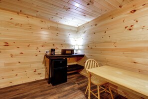A small, cozy room with wooden walls and a wooden floor. It includes a desk with a computer, a chair, and a lamp. - Letchworth Cabin: Lake Access, Slide, Canoe Rental (Bliss)