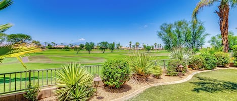 A golf course with a clear sky, well-maintained grass, and various plants.