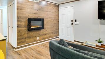 A living room with a fireplace, a sofa, and a television mounted on the wall.