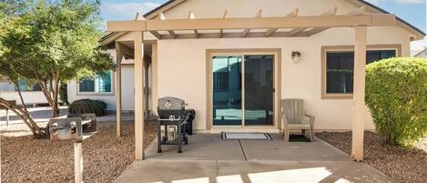 A covered patio with a grill, a chair, and a mailbox.