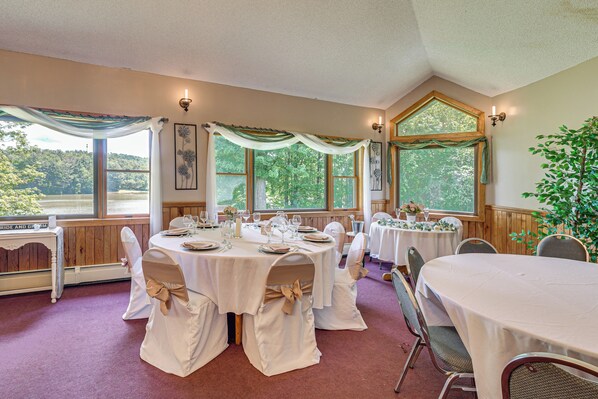 A banquet hall with round tables, white tablecloths, and chairs with beige sashes.