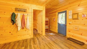 Interior de una cabaña de madera con un pasillo que conduce a una puerta, un letrero que dice 'LAKE' y un letrero de 'NO FUMAR'.