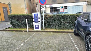 A parking area with a no parking sign, a pay station, and a building with multiple windows in the background. - T3 Montluçon-gare à 15 min à pied (Montluçon)