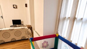 A room with a playpen, a bed, a television, and a door. - T3 Montluçon-gare à 15 min à pied (Montluçon)