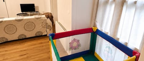 Una habitación con una alberca para bebés, una cama, un televisor y una puerta.