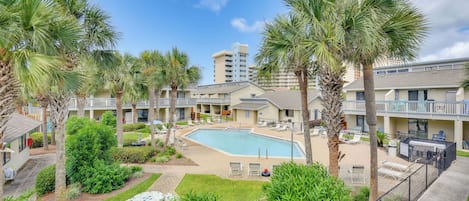 Ein Hotel mit Swimmingpool, Palmen und einem gepflegten Garten.