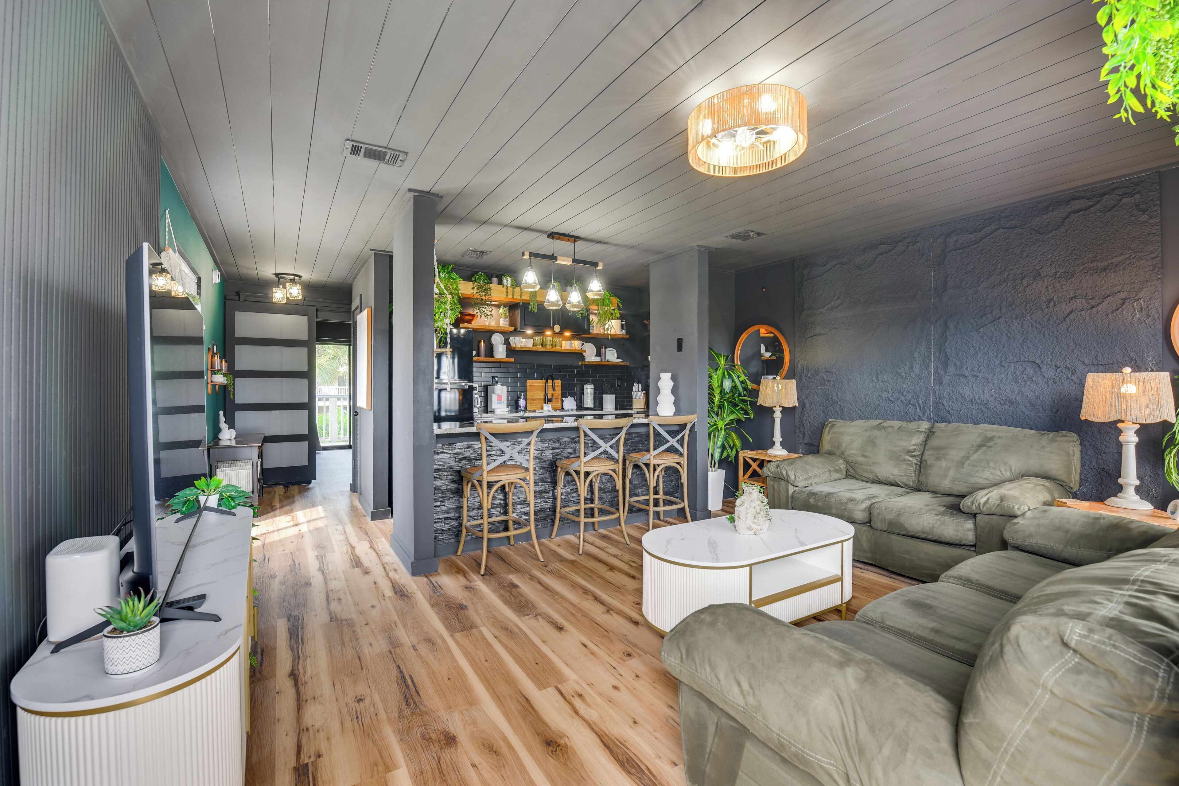 A modern living room with a sofa, coffee table, and bar area with stools.