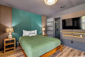 Ein modernes Schlafzimmer mit einem grünen Bett, Holznachttischen, einem Flachbildfernseher und einer integrierten Ablagefläche.