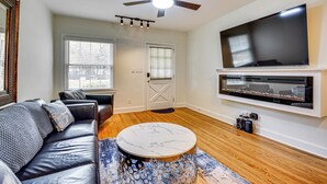 A modern living room with a leather sofa, a marble coffee table, a flat-screen TV mounted on the wall, and a ceiling fan. - Corner Unit 2 Mi to UNCG & Downtown Greensboro! (Greensboro)