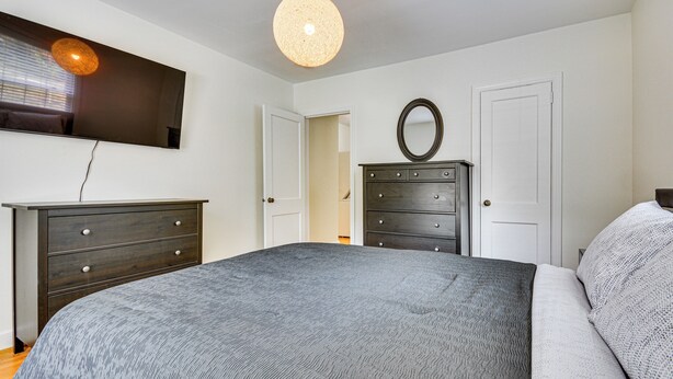 A bedroom with a bed, a dresser, a mirror, and a television on the wall. - Corner Unit 2 Mi to UNCG & Downtown Greensboro! (Greensboro)