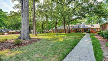 A residential area with a paved walkway, brick houses, and a large tree.