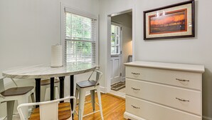 A dining area with a round table, two chairs, a white cabinet, and a framed picture on the wall. - Corner Unit 2 Mi to UNCG & Downtown Greensboro! (Greensboro)