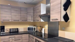 Una cucina moderna con mobili in legno, una cappa aspirante in acciaio inossidabile, un forno a microonde e un lavandino.