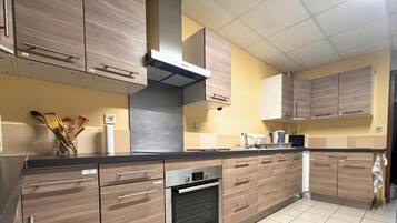 Une cuisine avec des armoires en bois, une hotte de cuisinière en acier inoxydable et un dosseret carrelé.