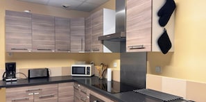 Eine moderne Küche mit Holzausstattung, einer Edelstahl-Dunstabzugshaube, einer Mikrowelle und einem Spülbecken.