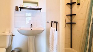 Et badeværelse med vask, toilet og brusebad.