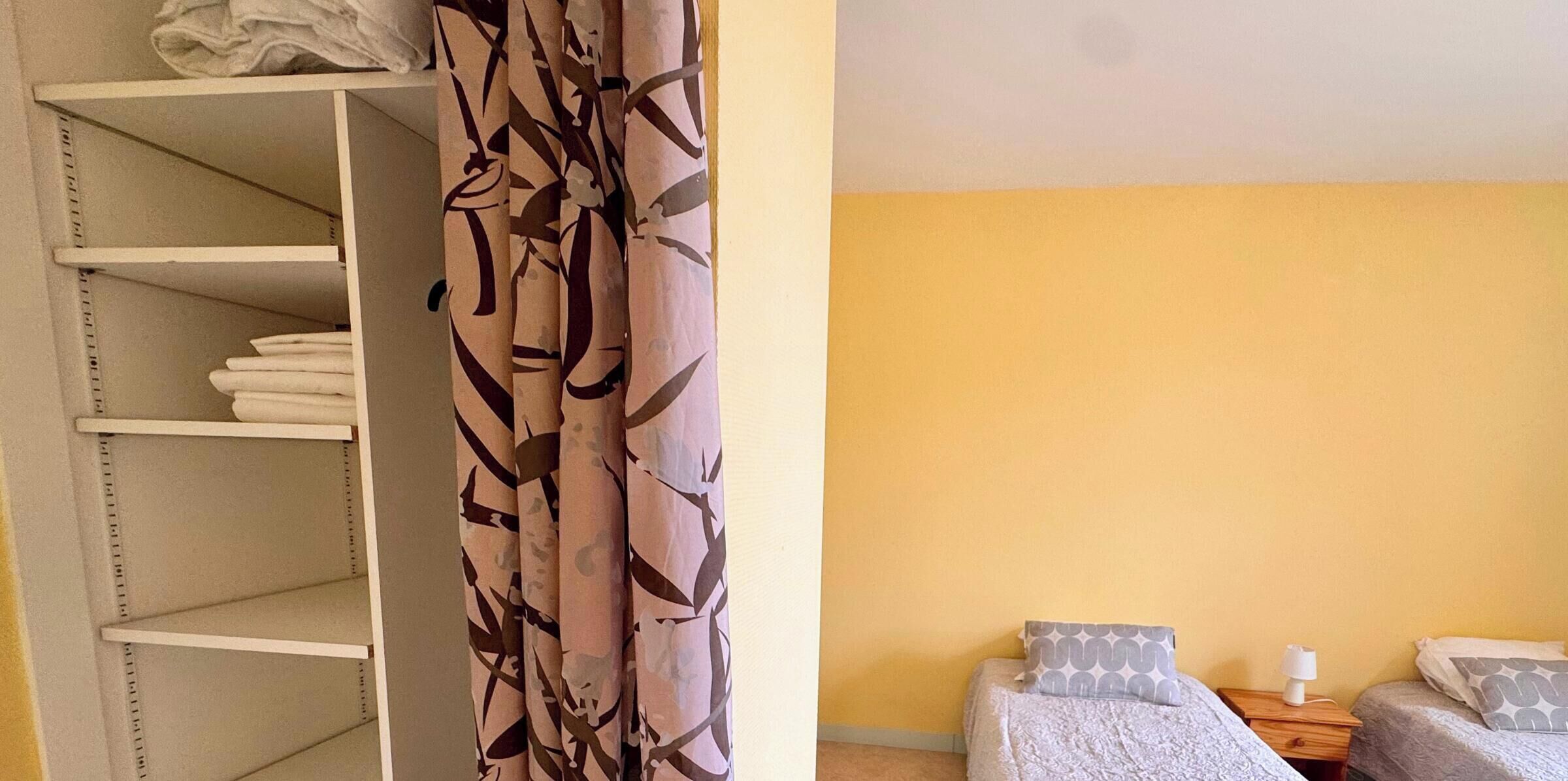 A room with a bed, two bedside tables, and a wardrobe with shelves.