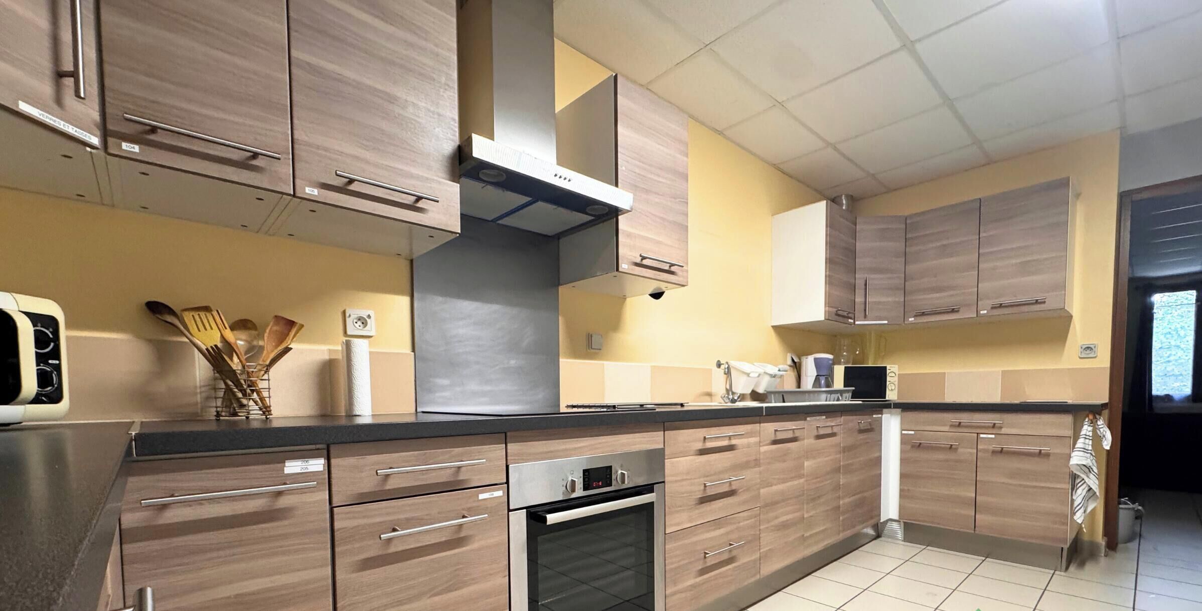A kitchen with wooden cabinets, a stainless steel range hood, and a tiled backsplash.
