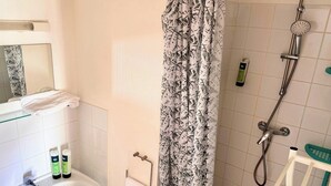 Un baño con ducha, toallero y espejo.