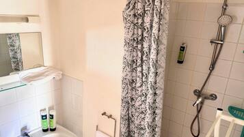 Une salle de bain avec une douche, un porte-serviettes et un miroir.