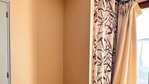 Habitación de hotel con dos camas, un sillón estampado y una ventana con cortinas.