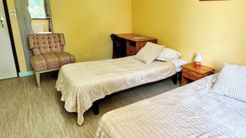 Quarto com duas camas, uma cadeira, escrivaninha e janela.