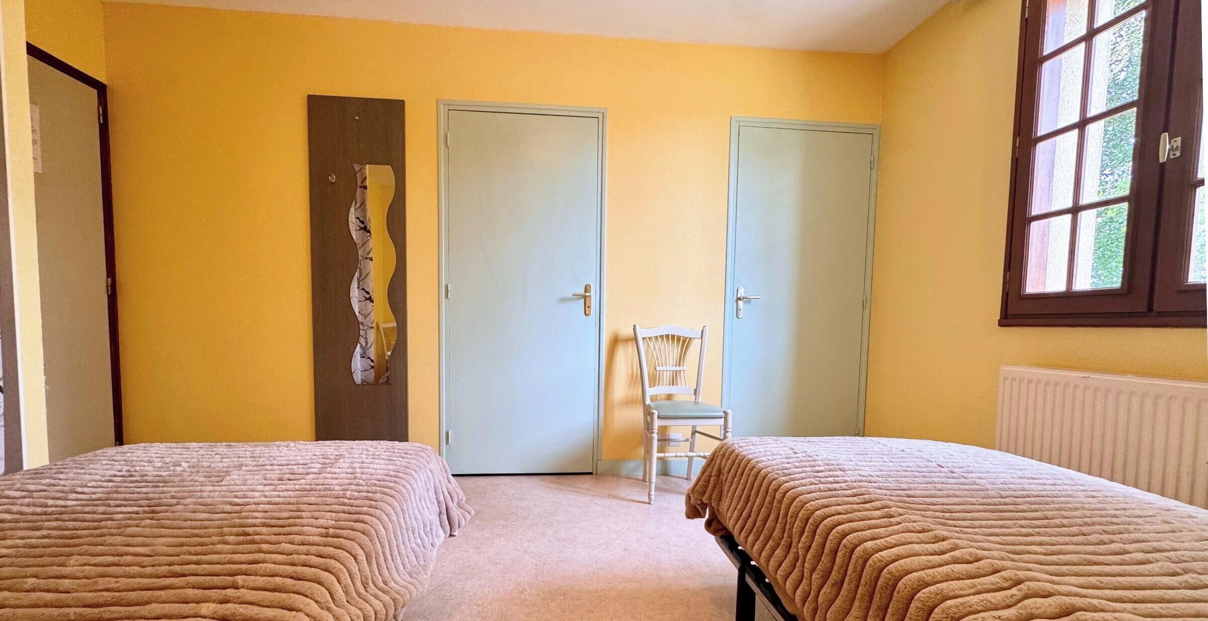 Une chambre avec deux lits, une chaise et deux portes.