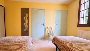 Una habitación con dos camas, una silla y dos puertas.